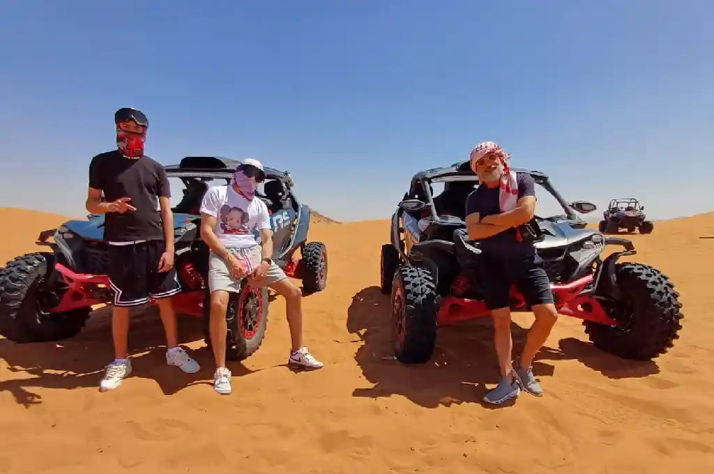 Group of riders sitting on Can-Am buggies on the dunes